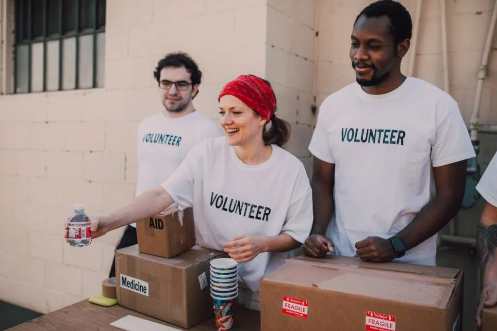 Three volunteers in white T-shirts giving out food