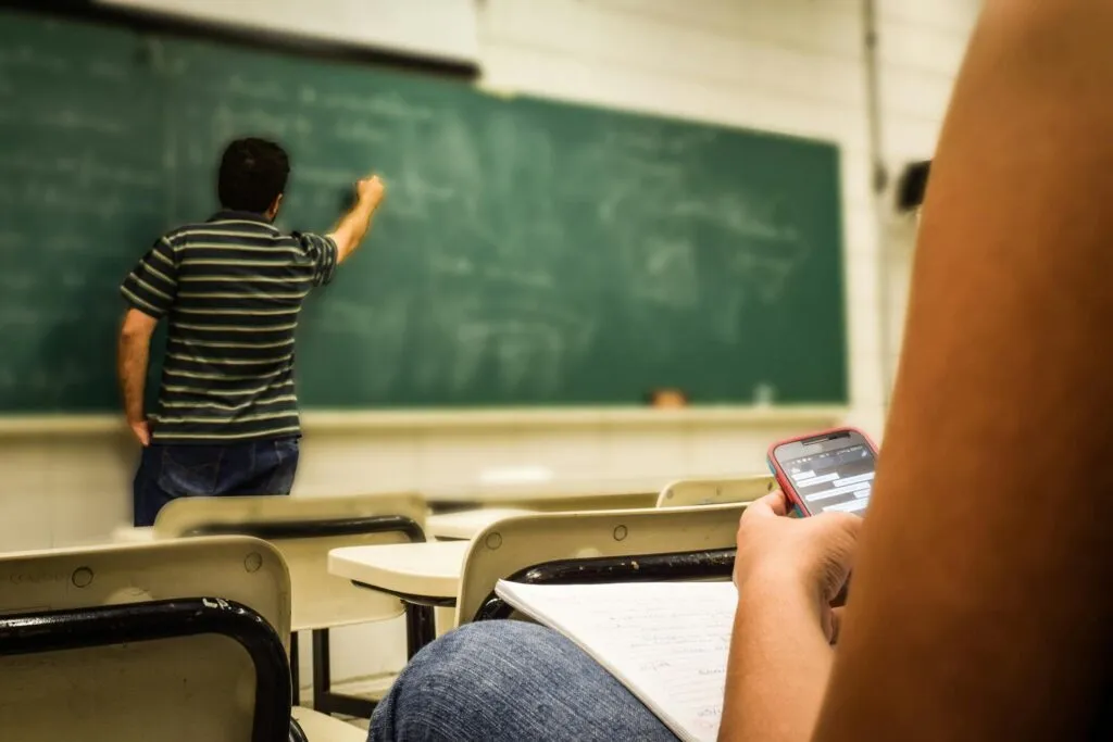 A teacher in a polo shirt writing on a writing board.