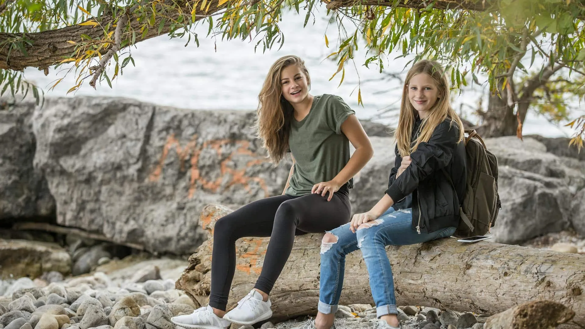 Two women sitting on a rock during the daytime.