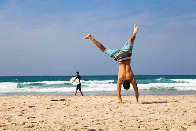 A man doing a handstand on a beach