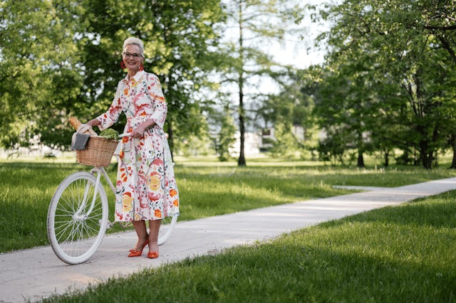 older woman with a bike in a park