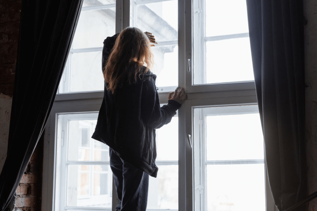a person looking through a window
Caption: Expats may face loneliness, homesickness, identity shifts, and the pressure to stay positive.